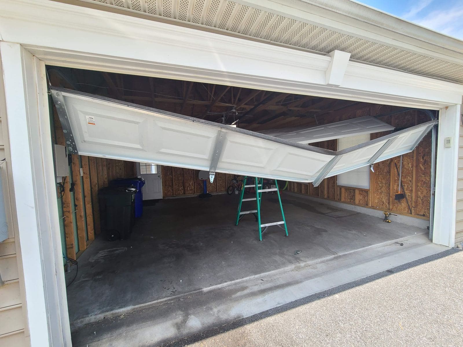 Garage door with sections folded and bent after a failure