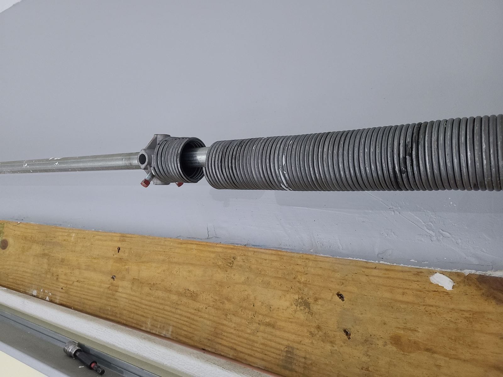 Torsion spring wound on the shaft above a garage door